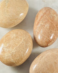 Peach Moonstone palm stone by Sarah Belle, with healing energy and relaxation properties.