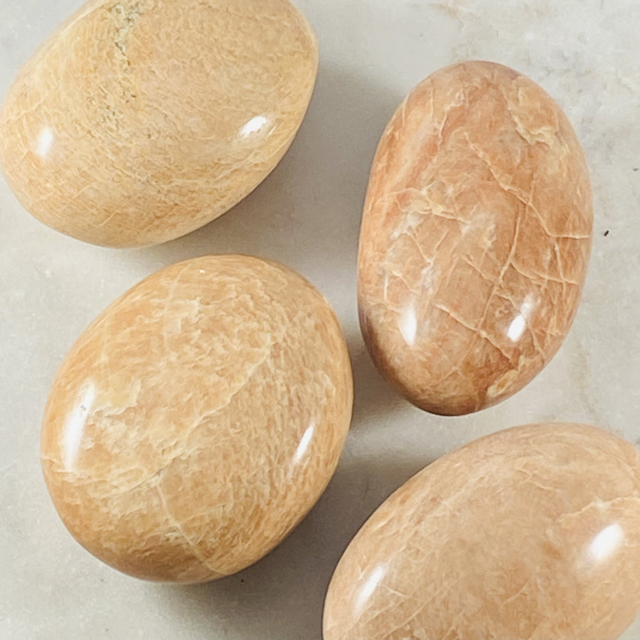 Peach Moonstone palm stone by Sarah Belle, with healing energy and relaxation properties.